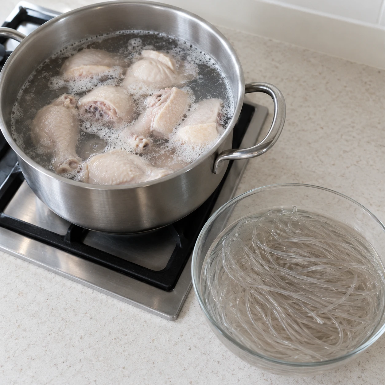 ขั้นตอน 1: แช่เส้นและเตรียมไก่ คลุม ¼ ของเส้นแก้วมันเทศเกาหลีจำนวน 1 ห่อของ 400 ด้วยน้ำเย็นธรรมดา และแช่ไว้ประมาณ 30 นาทีขณะเตรียมส่วนที่เหลือ ใช้ชิ้นไก่ติดกระดูก 800 ขนาดเล็กแพ็ค 1 กรัม ซับให้แห้งโดยไม่ต้องล้างไก่ดิบ ใส่ไก่ลงในหม้อที่มีน้ำเพิ่มเพื่อปิด นำไปต้มและต้มนาน 3 นาที สะเด็ดน้ำและทิ้งน้ำนี้ ขจัดฟองที่หลุดออก และทำความสะอาดหม้อ ไก่ยังสุกไม่เต็มที่