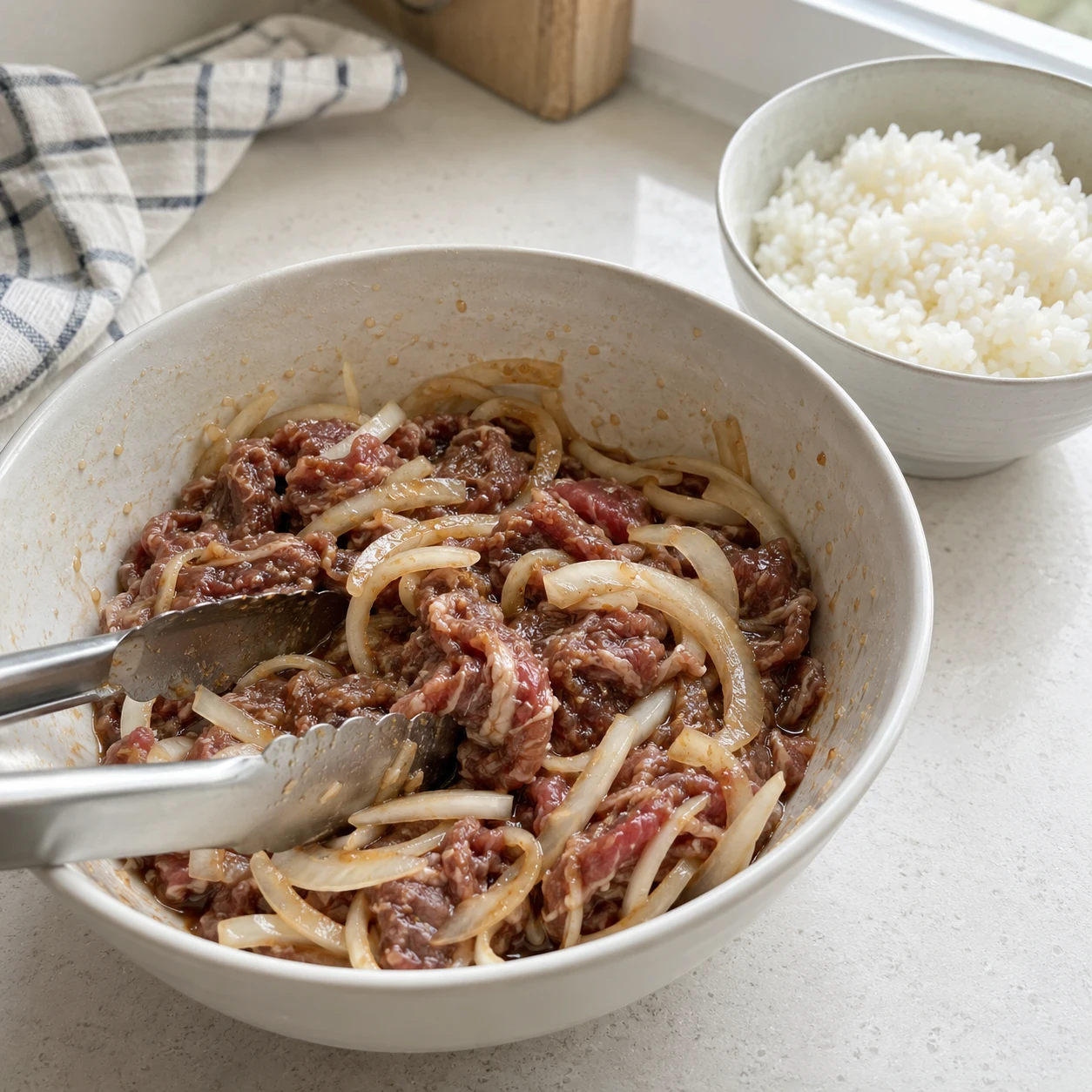 Step 2: Mix soy sauce, sugar, garlic, sesame oil and 3 eating spoons of water. Toss with the beef and onion and leave in the refrigerator for 10 minutes. Warm the cooked rice separately.