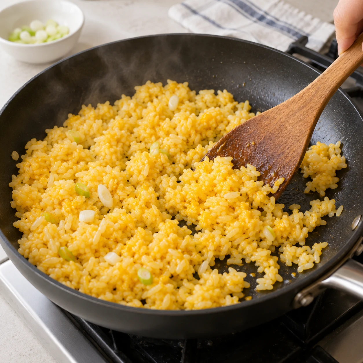 Step 5: Spread the rice in a thin layer, then turn and separate it repeatedly for 3–4 minutes over medium to medium-high heat. Keep the grains moving without crushing them; lower the heat if they scorch. The yolk coating must be completely set with no wet raw patches, and the rice piping hot throughout. For chilled leftover rice, aim for 74°C if checking with a thermometer.