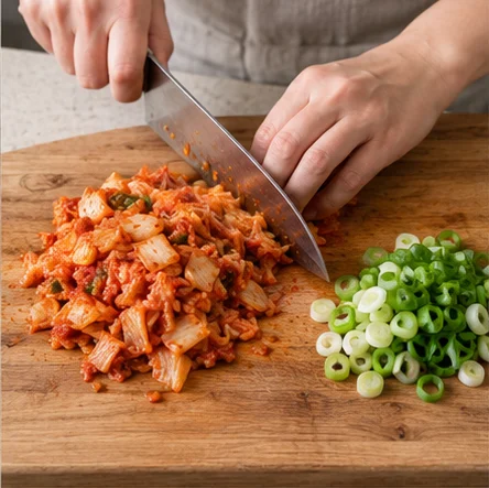 Paso 1: Usa arroz recién cocido o refrigerado rápidamente tras cocinar, nunca dejado horas fuera. Separa los grumos. Corta el kimchi en trozos pequeños y la cebolleta en aros.