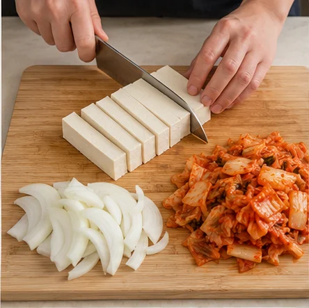Étape 1: Coupez 200 g de tofu en morceaux épais, 100 g d’oignon en lamelles et 200 g de kimchi en morceaux. Émincez l’oignon nouveau. Pour une version végétarienne, choisissez un kimchi sans poisson ni pâte de crevettes.